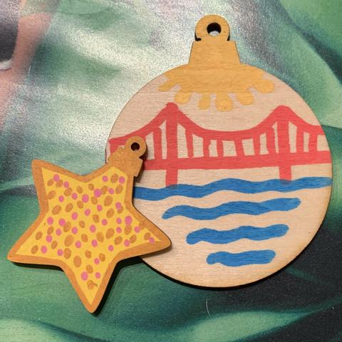 A round ornament with a suspension bridge and a star with colorful dots