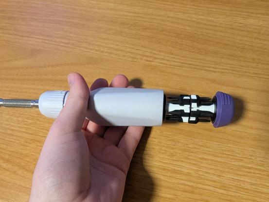 The LTT screwdriver in my hand, with the bit storage open.