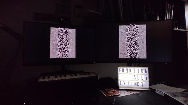 Lightbox with words 
FUNKTION
ALLY
EXTINCT
beneath two monitors, in the dark