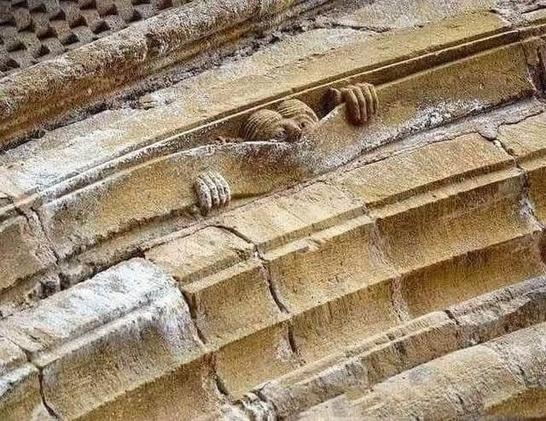 The Medieval mason who did this definitely had quite a sense of humor

A photograph of some medieval stonework - possibly an archway - where a man's face and hands are peeking out from one section