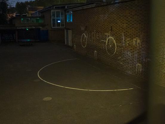 In a playground, there is the appearance of a face from two circles with dots in the centre on a wall, and a large semi-cricle on the ground below