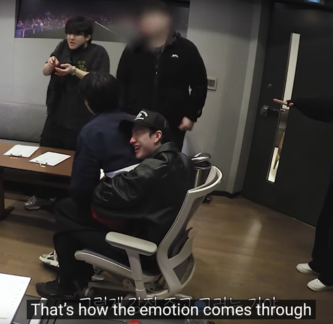 Changbin, Seungmin, Bang Chan and staff in a recording studio. Changbin is standing and explaning something. Chan sits in an office chair with Seungmin on his lap. He has his arms around Seungmin's waist and the side of his face pressed into Seungmin's back, and he's laughing with delight. Caption: that's how the emotion comes through