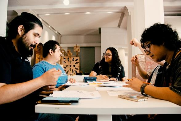 Fotografía, plano medio. Personas alrededor de una mesa jugando rol.