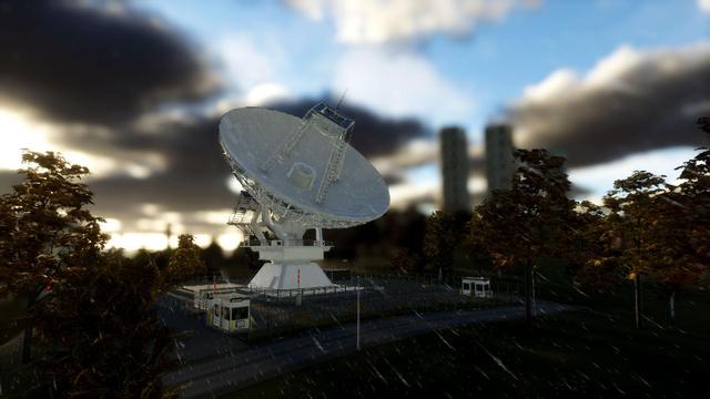 A radio telescope pointing up to a clouded sky opening up. Behind, on the right, two high raise are out of focus in the background.