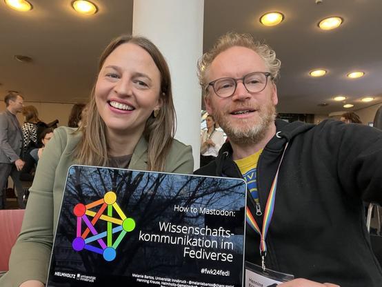Selfie: Melanie und Henning auf dem Forum Wissenschaftskommunikation mit der Start-Folie unseres Mastodon-Workshops auf einem Notebook