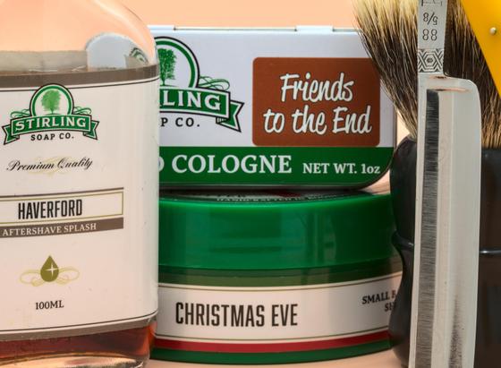 A combo of Stirling Christmas Eve soap, Haverford splash, and Friends to the End solid cologne with Puma 88 straight leaning against a Dogclaration Mystery B16 brush