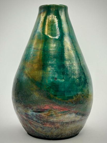 A dark green raku pottery vase with some hints of gold, metallics and reds.