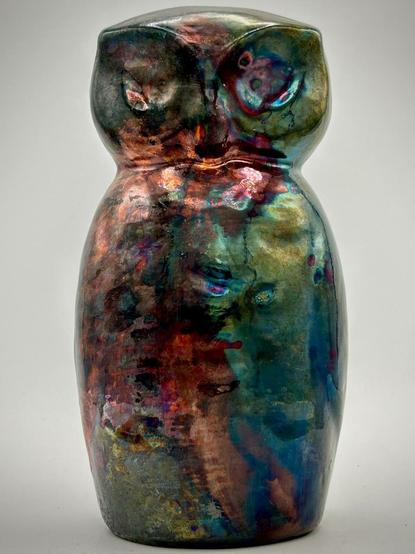 A raku owl with greens, red and iridescent effects.