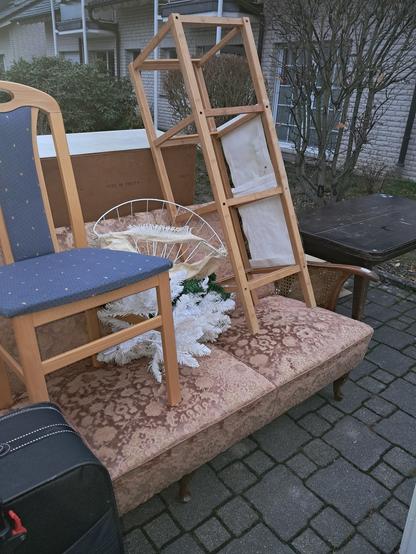 Übreblick zur Sperrmüllstelle. Zu sehen ist das Sofa, mit dem Stuhl drauf und ein ausgeschlachtetes einfaches Holzregal. Dahinter steht ein Tisch aus den 40ern, der sowohl in der Höhe wie auch Länge verändert werden kann. So einen Tisch hatten auch meine Großeltern, die daran aßen und sogar ihre Kaffeerunden mit Freunden abhielten. (Der Tisch ist immer noch da, nur nicht bei mir.)