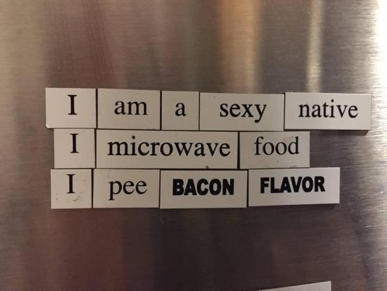 A collection of magnetic words on a refrigerator spells out "I am a sexy native," "I microwave food," and "I pee bacon flavor."
