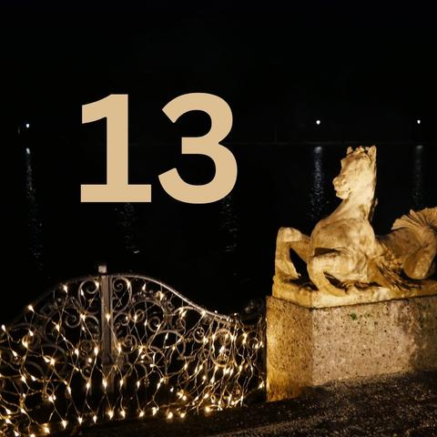 Stone horse in the dark as part of a porte that is illuminated by golden lights. In the middle the number 13.