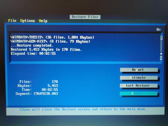A photo of a colour TFT screen showing the TUI (fullscreen text user interface) of the "Restore Files" page of the Fastback Pro DOS application. The colour scheme is light blue, dark blue, white and grey with yellow highlights on certain letters of menus and buttons, indicating the keystroke that'll trigger that operation.

The top part of the UI is a log of the restore operation. It shows the following summary: 

Restore completed.
Restored 5,453Kbytes in 170 files.
Elapsed time: 00:02:55