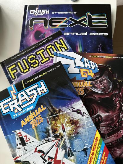 Three A5 Christmas annuals Crash, Zzap64 and Fusion on top of an A5 Next annual