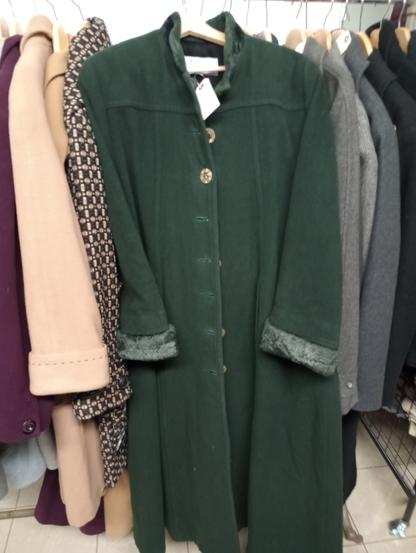 a large deep green winter wool coat hanging on a rack of wool coats