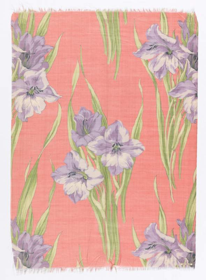 A realistic fabric/wallpaper design of purple irises, with green stems and leaves, on a pink/orange background.
