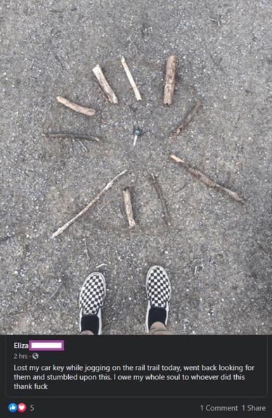A pair of checkered shoes is standing on a gravel path. In front of the shoes, several sticks are arranged in a circular pattern with a car key placed in the center. The text below the image is a social media post that reads: 'Lost my car key while jogging on the rail trail today, went back looking for them and stumbled upon this. I owe my whole soul to whoever did this thank fuck.