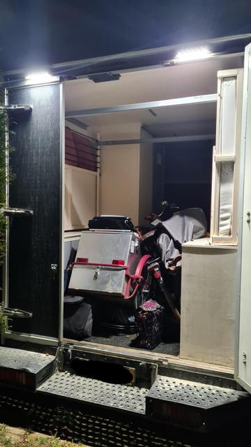 The back of an open truck, cart and bicycle side by side between wooden RV furniture.