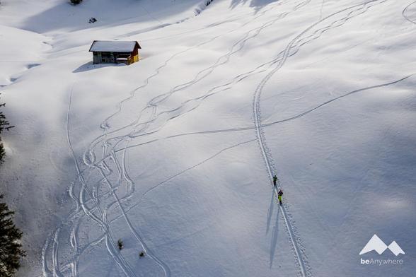 Drone image of two people ski touring in a wintery landscape.