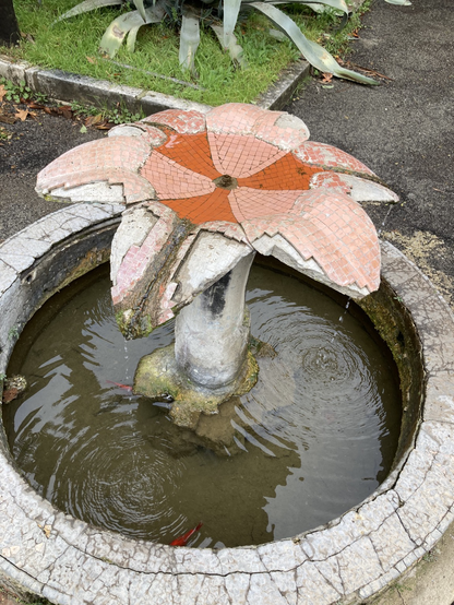 La foto mostra una piccola Fontana a forma di fiore con grandi petali rossi