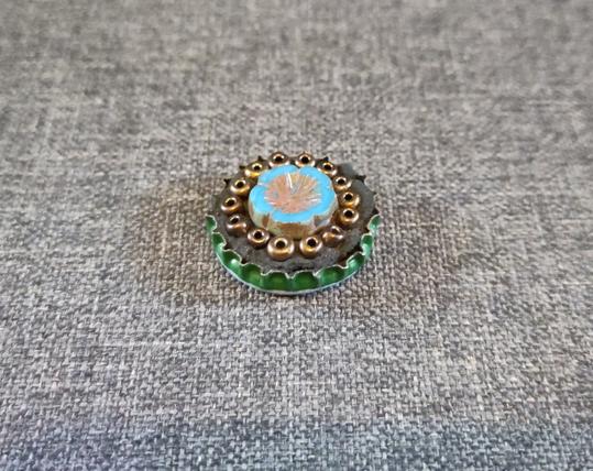 A small flower fridge magnet made from beads and a bottle top