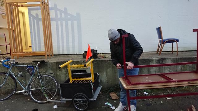 Un homme, du mobilier et un vélo avec remorque