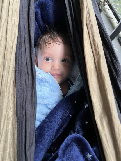 A smiling baby inside a hammock.