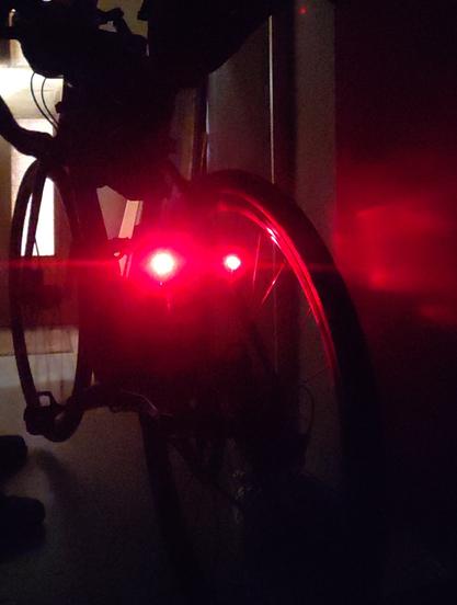 Fahrrad im Keller. Von hinten. Die zwei Rücklichter an den Sattelstreben leuchten sehr hell