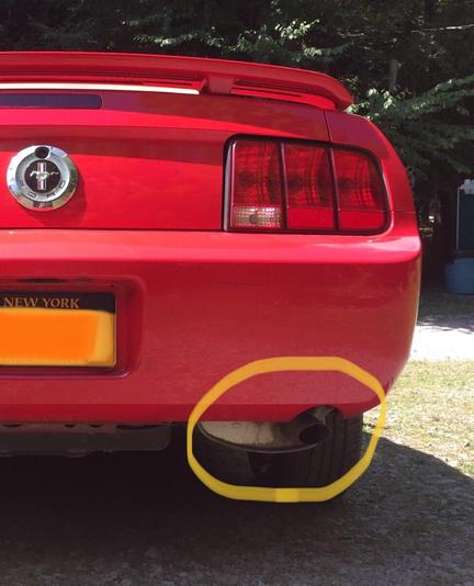 A Before picture of my stock muffler, circled in yellow. After 100K miles, the 2.5 inch exhaust pipe is rusted.