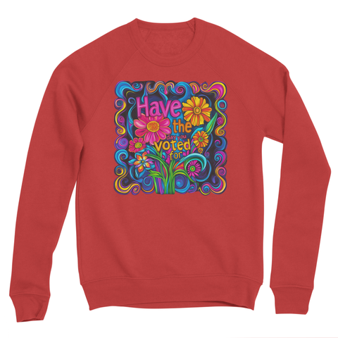 A red sweatshirt with a colorful, psychedelic flower design on the front. The design features vibrant flowers and swirling patterns in shades of blue, pink, yellow, green, and purple. Centered in the design is text that reads, "Have the day you voted for!" in bold, colorful lettering, surrounded by stylized flowers and leaves. The sweatshirt has a relaxed fit and a crewneck style.