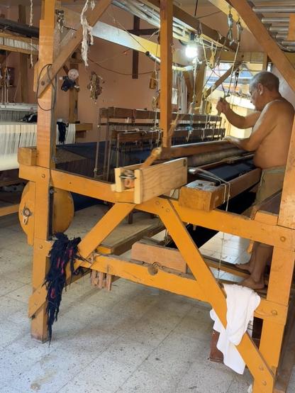 A shirtless man working a wooden loom