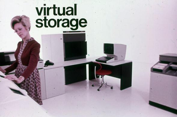 A female technician operates a mainframe computer in the 1970s on a white background.  Helvetica text says "virtual storage" behind her