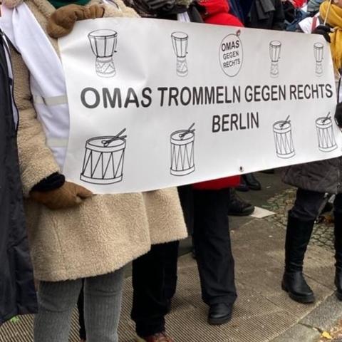 Foto: Frauen halten ein weißes Banner mit schwarzer Schrift: Omas trommeln gegen Rechts Berlin
Darauf auch Skizzen verschiedener Trommeln