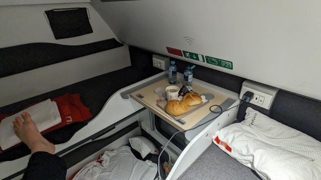 A modernized nightjet compartment with breakfast on the upper couchette shelf.