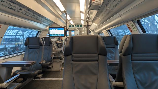 A regional train from inside in first class featuring comfortable, adjustable chairs and broad tables.