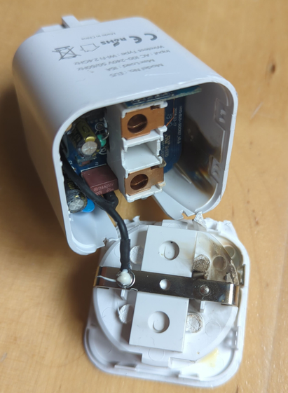 Ein Bild von ein einer auseinandergeschraubten WiFi faehigen Steckdose. Im Inneren der Steckdose sind geschmolzene Plastikteile sichtbar.