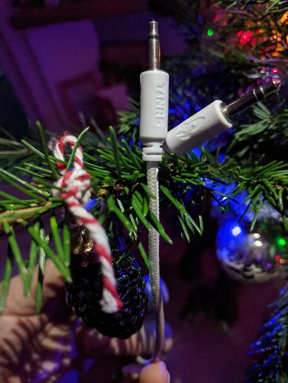 Picture of our white patch cables with TiNRS and a Rocket on the plugs crossing over a small branch in a christmas tree, fairy lights and red/white string are also in the tree