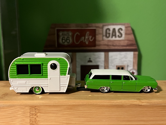 A green 1962 Chevy Biscayne station wagon toy with a trailer made by Maisto