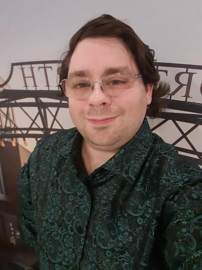 Me wearing a green and black silk shirt, with glasses, and wavy brown hair
