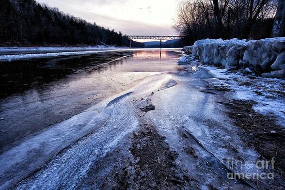 Ice on the Delaware River is a color photograph taken during winter with heavy ice on the water. The sunset sky and the bridge to Montague NJ in the distance