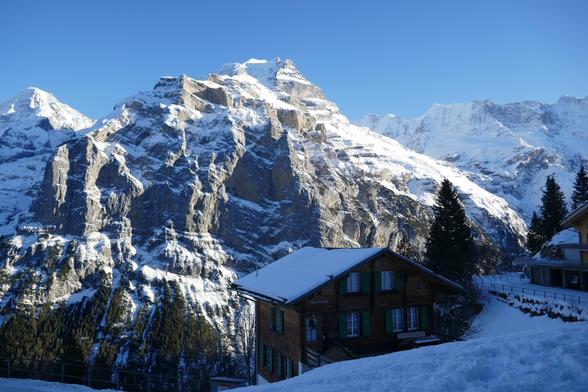 An old wooden hotel in a winter landscape with mountains in the back