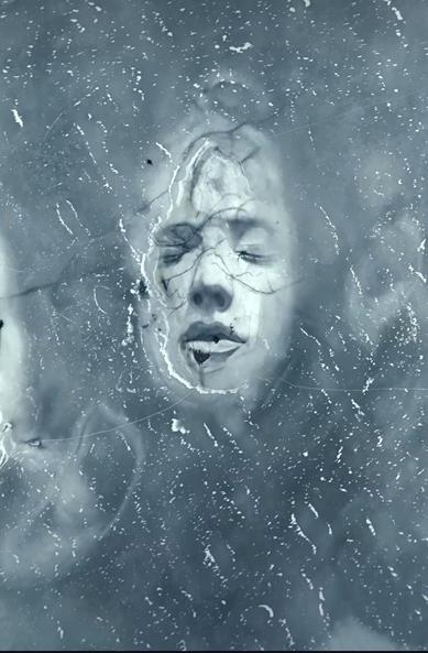 Photography. A color photo taken by drone shows an unusual and huge ground painting on a frozen island in the Baltic Sea. The island, surrounded by rippling ice edges, rises out of the frozen water and is the perfect canvas for a portrait of a woman's face. The picture shows the head of a woman with closed eyes, half submerged in the icy water. The dimension can be recognized by the fact that the artist is standing tiny next to the head on the ice. The huge work of art was created using only charcoal and water from an ordinary garden sprayer and will therefore disappear of its own accord.
Info: According to the artist, the artwork entitled "Emergence" is about renewal, resilience and the beauty of scars. It is a kind of baptism - a figure marked by the past, but resurrected and ready for something new.