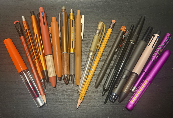 Collection of orange and purple writing tools on a black background