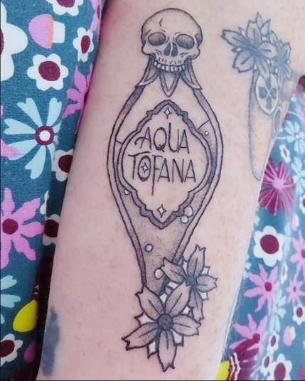 My new tattoo, on the back of my right arm. It's a potion bottle with flowers at the bottom of it. The cork stopper is in the shape of a skull, and the label reads AQUA TOFANA. There are tiny bubbles in the poison inside the bottle, and tiny stars on the label. The tattoo is very delicately done, which juxtapositions nicely with the deadly subject matter.