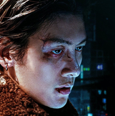 Ji Chang Wook in the 2024 South Korean drama "Gangnam B-Side." A close shot of the right side of his face all beaten-up, with cuts and blood. He is wearing a silver hoop earring & has a fake fur collar.