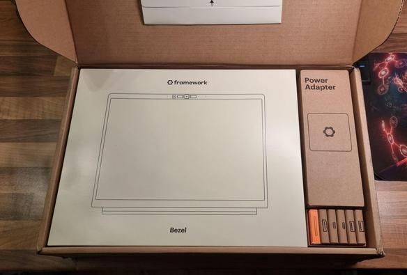 Karton mit dem Inhalt von verpackten Einzelteilen eines Framework Laptops.