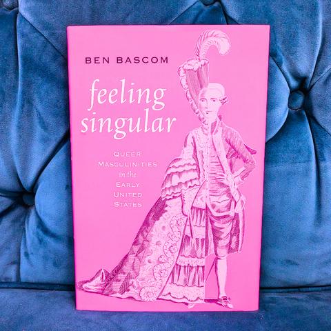 The book "feeling singular" by Ben Bascom on a blue couch