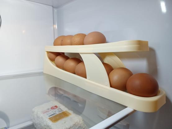 A plastic contraption inside a refrigerator. It forms two levels where eggs can sit on a slight slope. The fresh eggs are inserted at the top front and roll down and around a curved drop at the end, then forward again at the lower end, where the oldest egg can be easily retrieved at the front bottom. A first-in-first-out buffer.