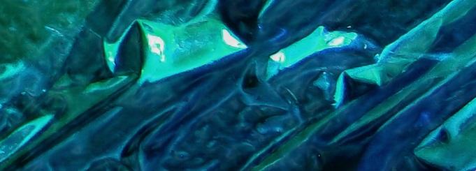 A zoomed-in, abstract image consisting of mostly blues & greens, with folds, creases & other qualities that are intended to suggest a crystal-like appearance, with reflected & refracted light at play in the image.