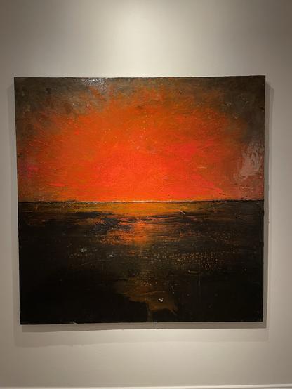Paakkolan maalaus, jossa on tyylitelty voimakkaan punaoranssi auringonlasku tumman veden yllä. Vesi heijastaa auringonlaskun värejä siltana ja pienempinä kimalluksina aalloilla.