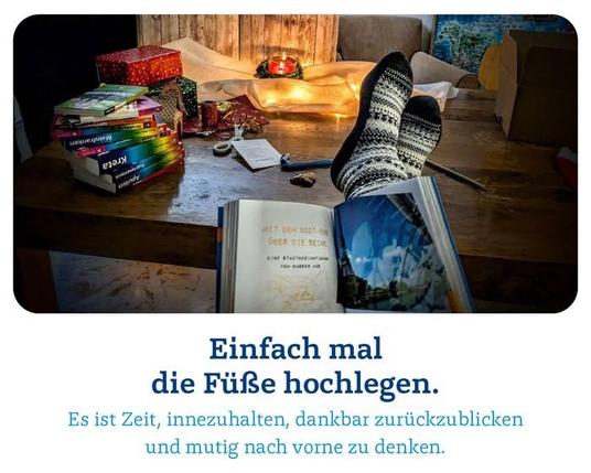 Ein Schreibtisch mit Adventlicht, Päckchen und MM Reiseführern; Stifte ...

Ein paar Füße darauf
und im Vordergrund ein aufgeschlagenes Buch
